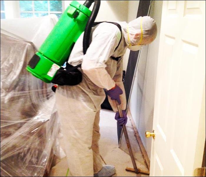 employee in PPE cleaning a floor