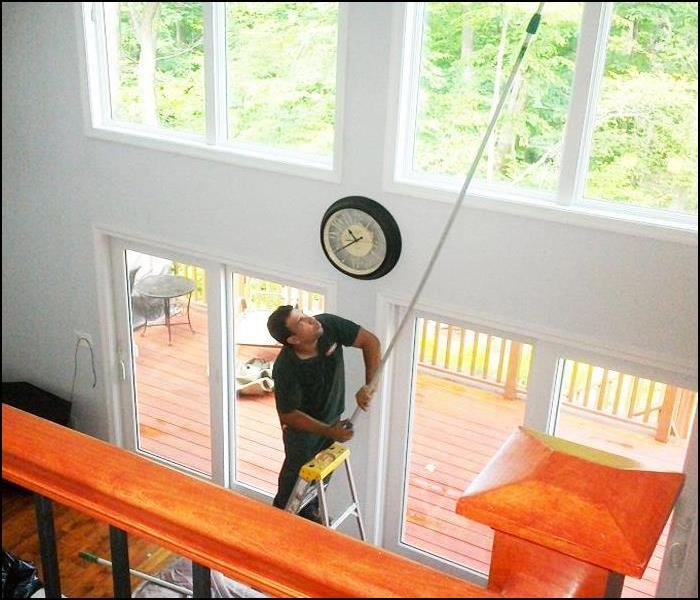 employee on a ladder cleaning windows