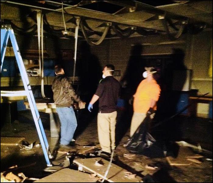 three employees standing in a home with fire damage