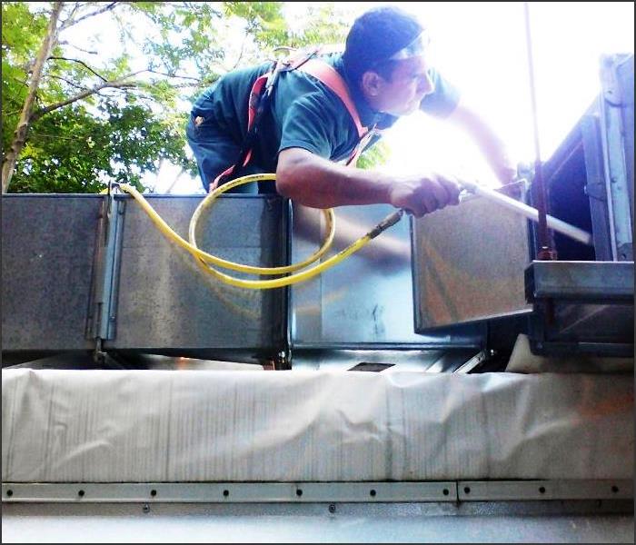 employee cleaning an HVAC system